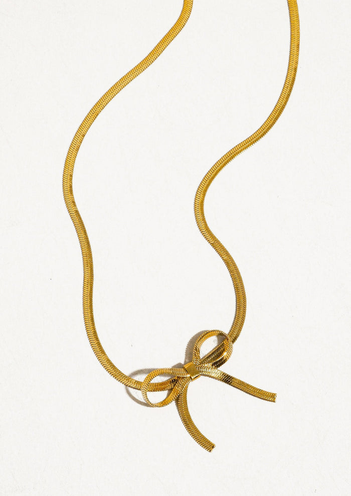 A gold choker-style necklace with bow shape at front.