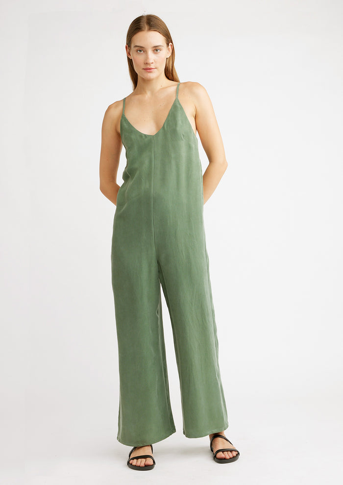 A woman wearing a green jumpsuit with black sandals