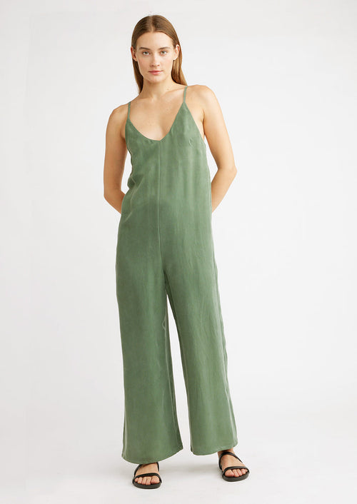 A woman wearing a green jumpsuit with black sandals