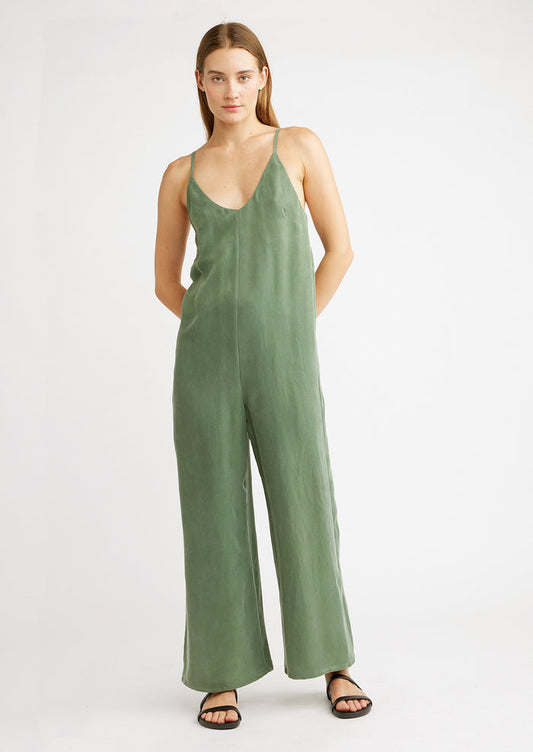 A woman wearing a green jumpsuit with black sandals