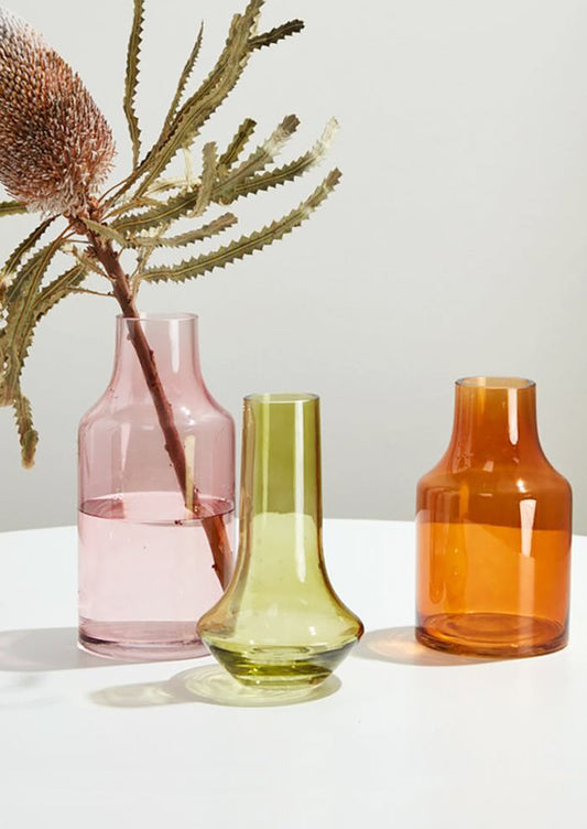 Three transparent glass vases in assorted colors and shapes.