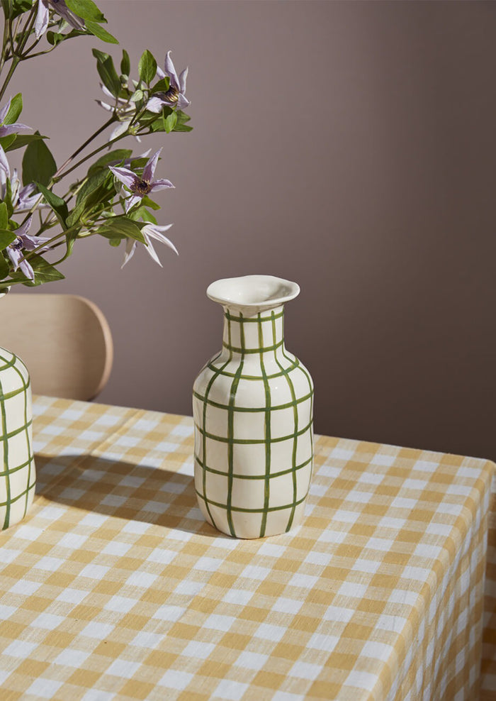 A ceramic vase in white with green grid pattern.