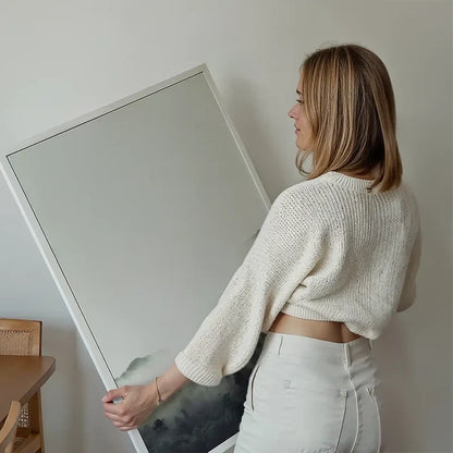 Woman holding a framed "Forest Print" with subtle green tones, a Scandi-style photographic print.