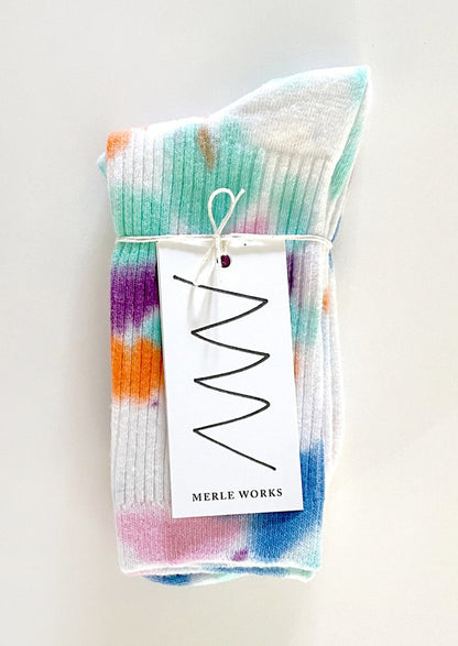 A pair of tie dye socks in white with bright aqua, blue, orange, pink and purple.