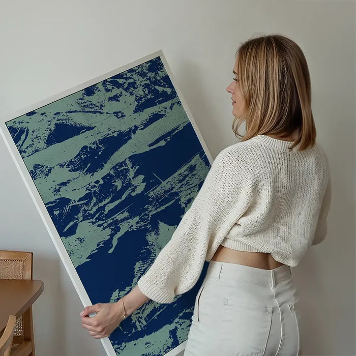 Woman holding a framed inky blue graffiti print on thick art paper, featuring urban style.