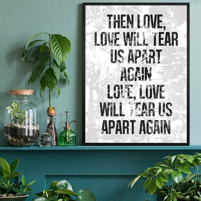 Framed white grunge print with "Love Will Tear Us Apart" lyrics in black, displayed on a green shelf.