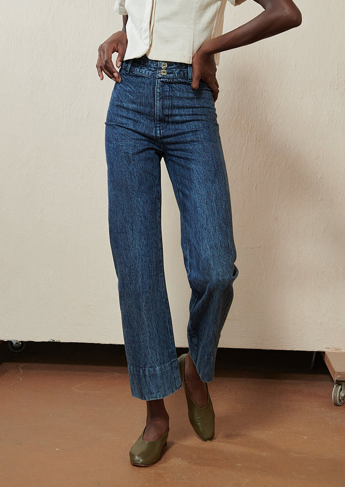 Woman wearing blue jeans and green flats.