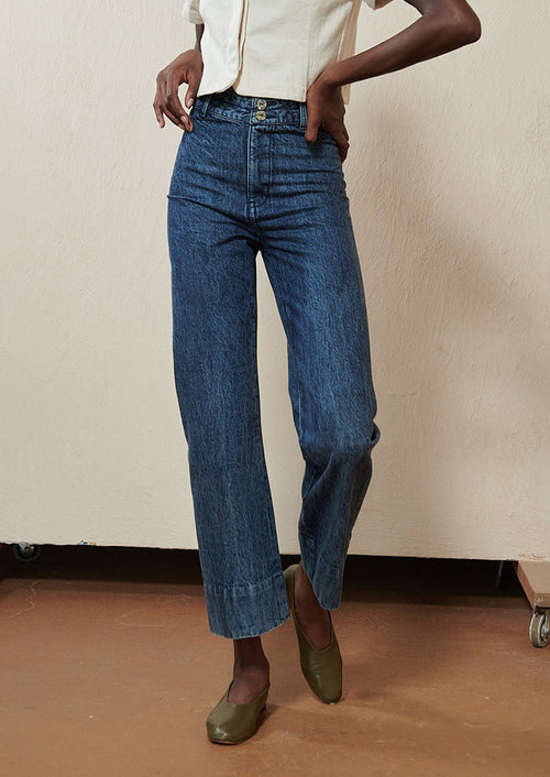 Woman wearing blue jeans and green flats.