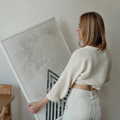 Woman holding a framed abstract dark marble point art print with a textured background.