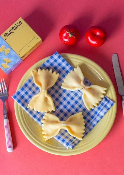 A candle in the shape of a piece of farfalle pasta.