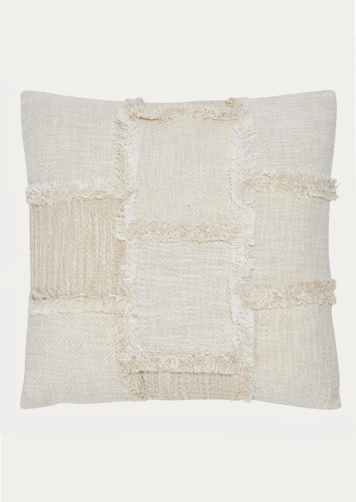 A throw pillow in natural cotton with patchwork detailing in different textures.