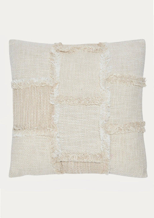 A throw pillow in natural cotton with patchwork detailing in different textures.