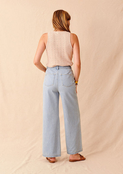Woman wearing light wash jeans, tank, and sandals, seen from behind.