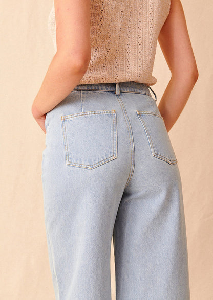 Woman wearing light wash jeans, seen from behind.