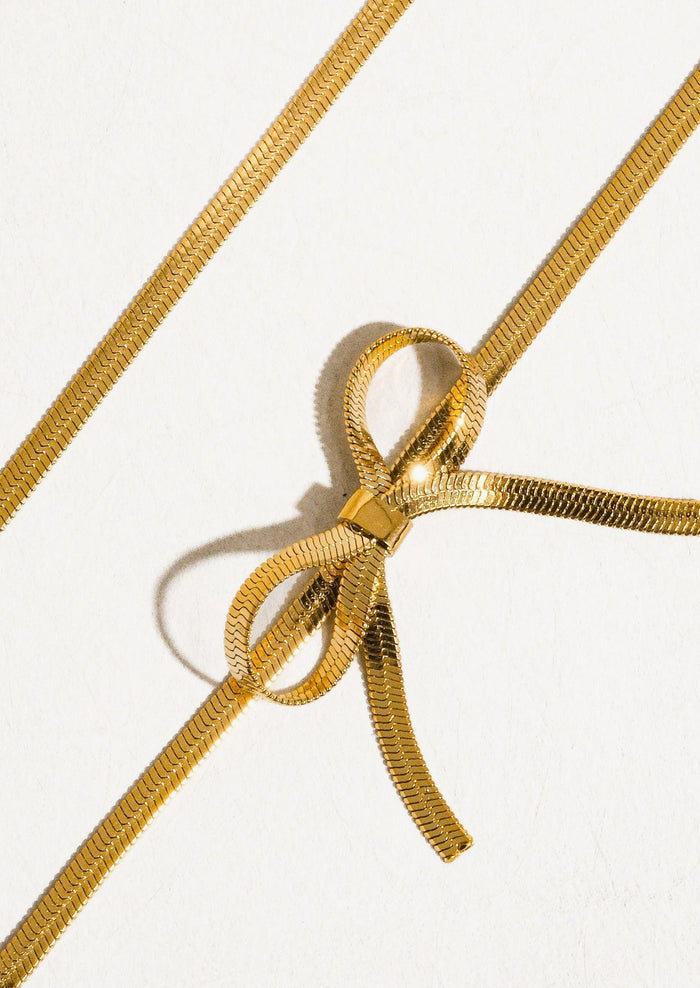 A gold choker-style necklace with bow shape at front.