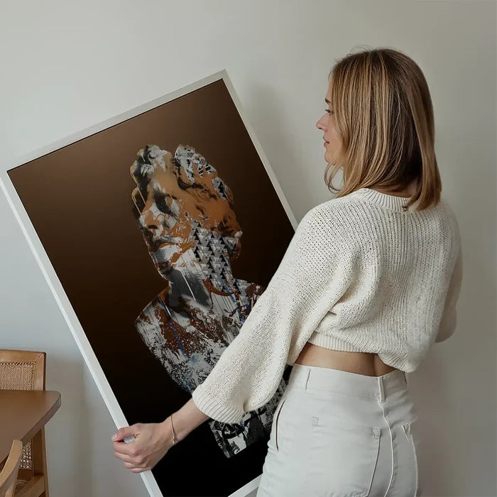 Woman holding a framed urban art print of a classic bust with colorful graffiti on a dark brown background.