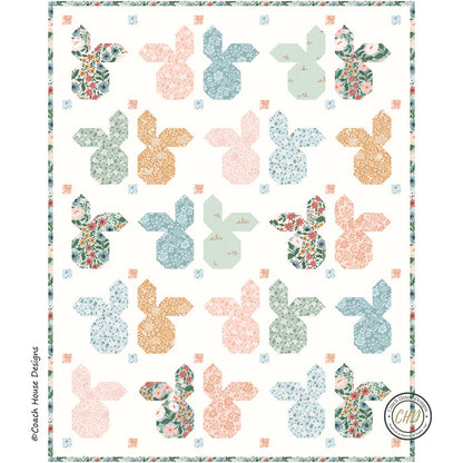 Close up of the lap quilt pattern, which is made of patterned fabric with colorful bunny head designs on a white background.
